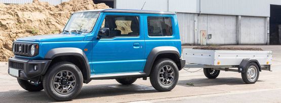 Blauer Geländewagen mit Anhänger voll Kompost